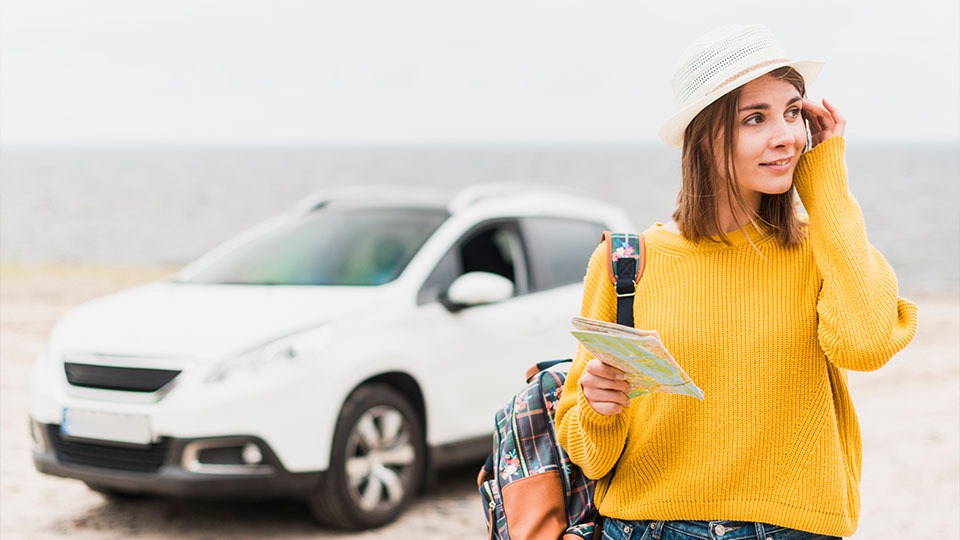 mujer turista en la playa con un coche de alquiler